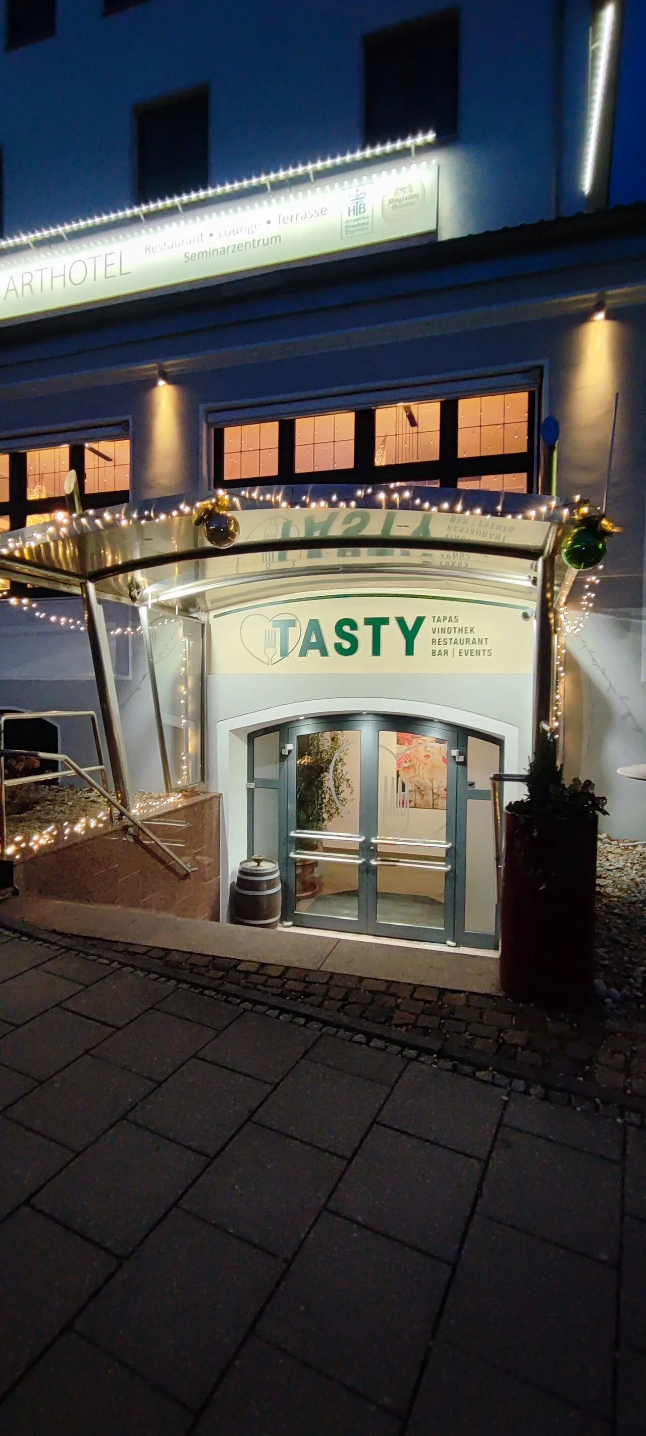 Beleuchteter Eingang des Tasty Restaurant in Herrsching